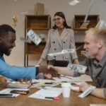 Joyful business colleagues celebrating a successful deal with handshake and flying money.